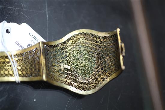A Chinese silver gilt filigree bracelet inset with three carved jadeite oval foliate panels.